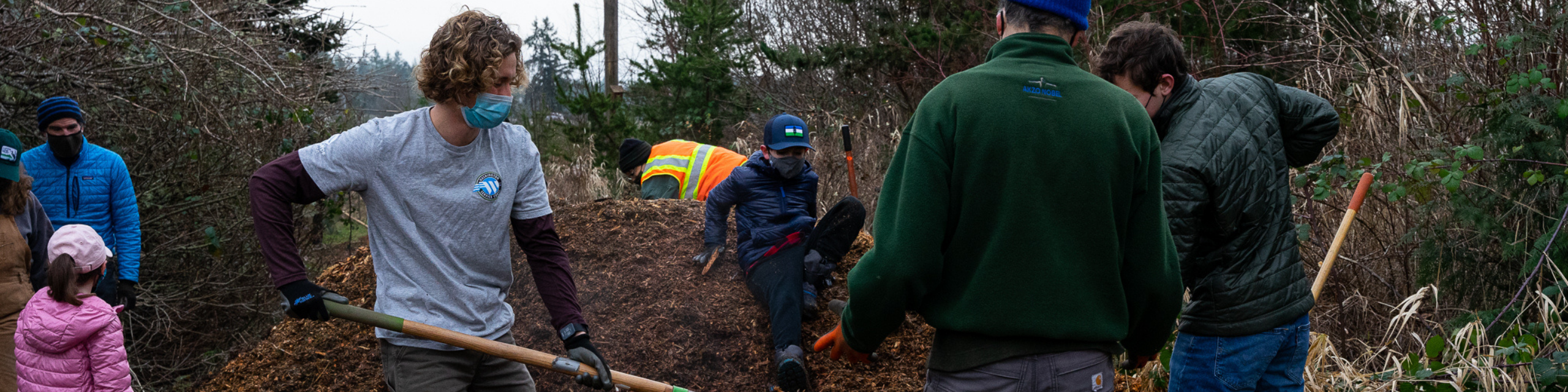 AmeriCorps member Sam with volunteers spreading mulch.